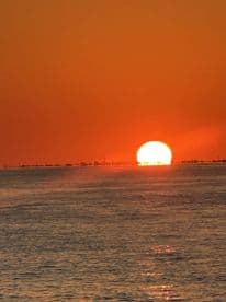 A breathtaking sunset over the ocean, casting vibrant orange hues across the sky and water — a perfect backdrop for evening boat cruises.