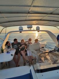 A joyful group celebrates aboard a boat at sunset, capturing the essence of a perfect party on the water.