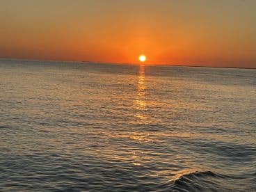 A stunning sunset over calm waters, creating a beautiful reflection — perfect for serene evening boat rides.