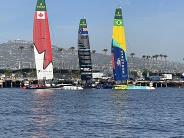 A vibrant scene from a sailing regatta featuring multiple yachts with colorful sails, showcasing the excitement of competitive sailing on the water.
