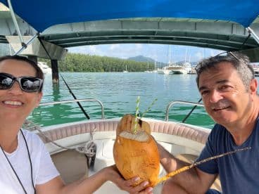 A couple enjoys refreshing coconut drinks aboard a boat, capturing a joyful moment on the water — perfect for tropical getaways and romantic adventures.