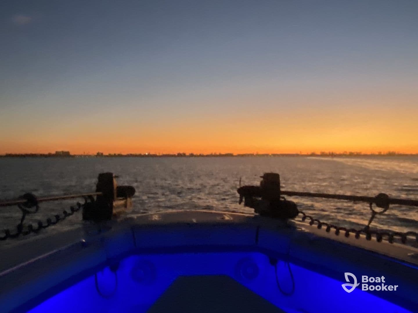 A serene sunset view from the bow of a boat, showcasing the tranquil waters and city skyline in the distance — perfect for evening cruises.