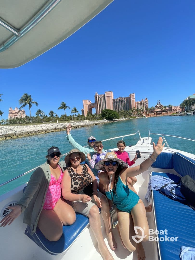 A joyful group of friends and family enjoy a day on the boat, celebrating under the sun with the stunning Atlantis resort in the background — perfect for memorable outings and adventures.