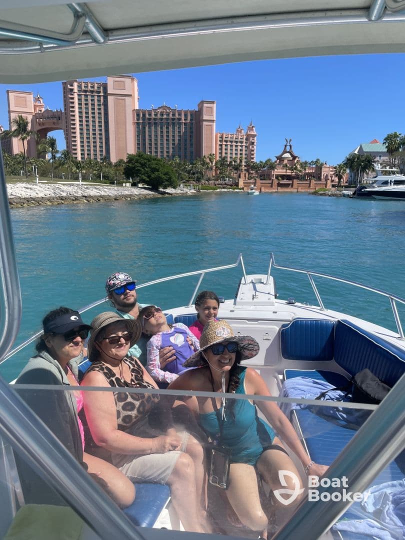 A joyful family poses together on a boat, enjoying a sunny day out with the stunning Atlantis resort in the background — perfect for memorable vacation moments.