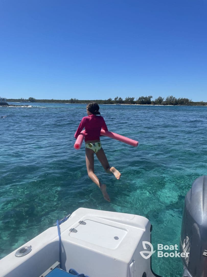 A child joyfully jumps into the clear waters with a pool noodle, capturing the essence of fun water activities during a boating adventure.
