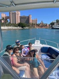 A joyful family poses together on a boat, enjoying a sunny day out with the stunning Atlantis resort in the background — perfect for memorable vacation moments.