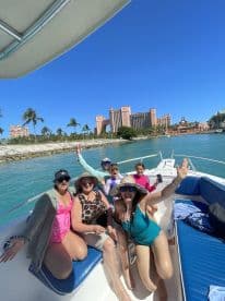 A joyful group of friends and family enjoy a day on the boat, celebrating under the sun with the stunning Atlantis resort in the background — perfect for memorable outings and adventures.