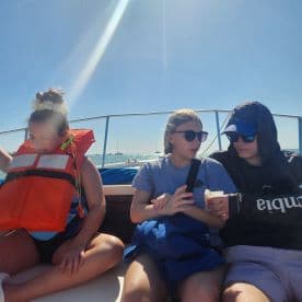 A group of young friends enjoys a sunny day on the boat, sharing snacks and laughter — perfect for a fun day out on the water.
