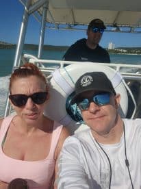 A couple enjoys a sunny day on the water, capturing a selfie aboard their boat — perfect for memorable adventures and fun outings.