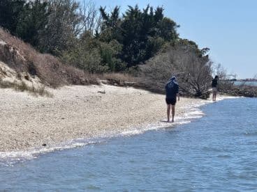 Two individuals stroll along a serene beach, enjoying the tranquil waters and natural beauty — a perfect scene for relaxation and exploration.