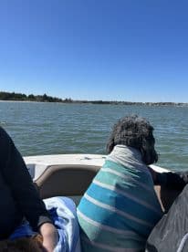 A cozy moment on the water with a dog wrapped in a towel, enjoying the scenic views from the boat — perfect for pet-friendly outings.