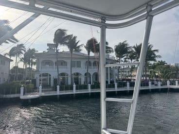 A scenic view of luxury waterfront homes framed by palm trees, captured from a boat, showcasing the beauty of coastal living.