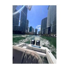 A sleek speedboat navigates through the vibrant waterways of a bustling city, showcasing stunning skyscrapers against a clear blue sky.