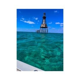 A stunning view of a historic lighthouse standing tall over crystal-clear turquoise waters, perfect for capturing the beauty of coastal landmarks.