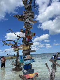 A vibrant display of personalized signs at a popular beach spot, with visitors enjoying the shallow waters and boats in the background — a perfect destination for fun and relaxation.