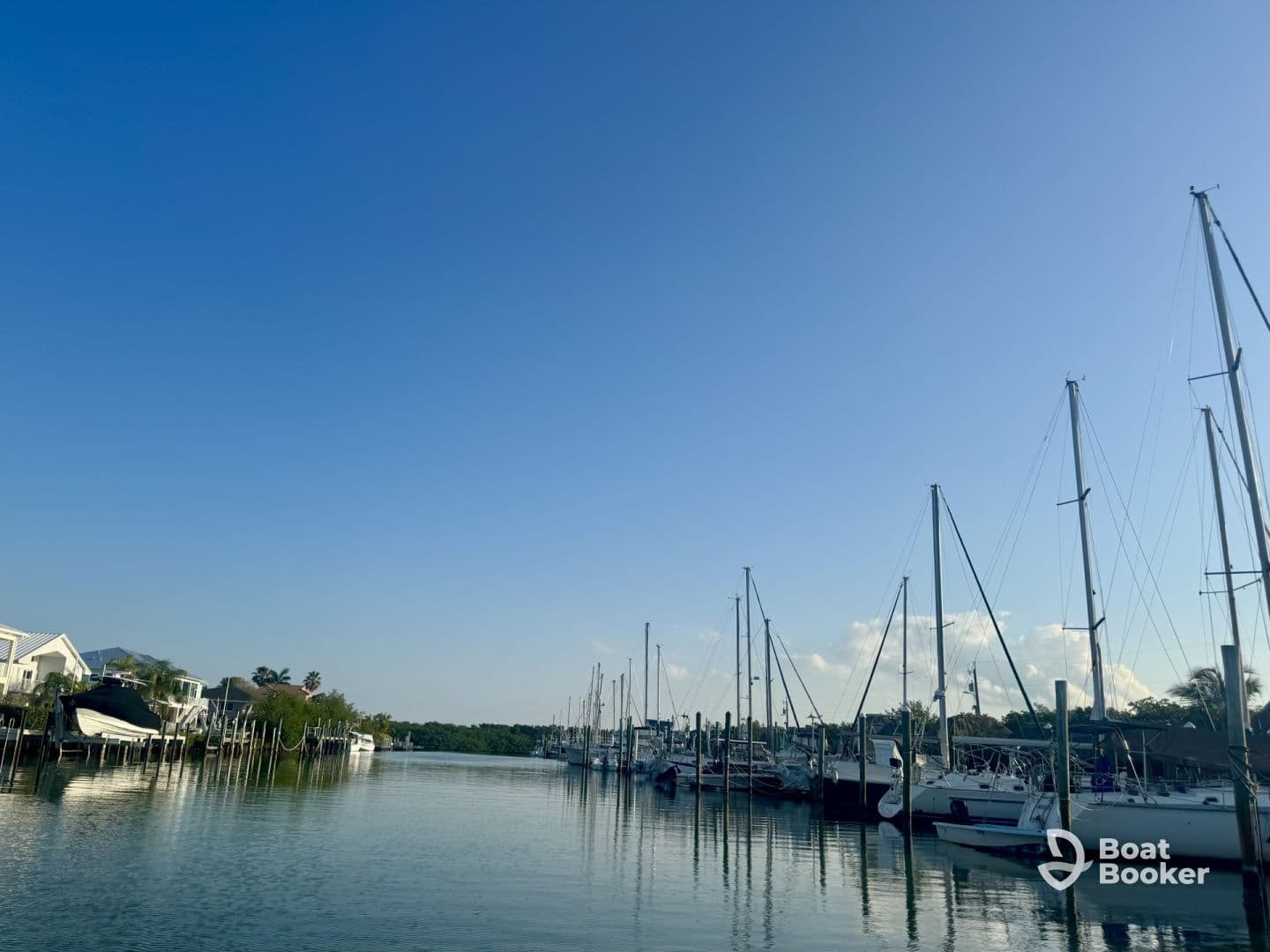 A serene view of a marina filled with sailboats, reflecting in calm waters under a clear blue sky — perfect for boat enthusiasts and those seeking a peaceful waterfront escape.