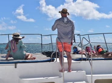 A family enjoys a sunny day on a boat, with children lounging and adults taking in the ocean views — a perfect setting for relaxation and fun on the water.