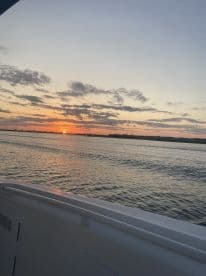 A serene sunset view from the deck of a boat, showcasing the tranquil waters and vibrant colors of the sky — perfect for evening cruises.
