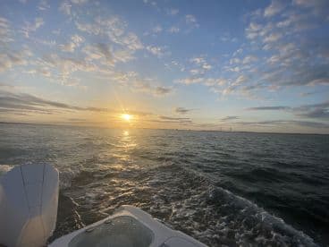 A stunning sunset view from a boat, showcasing the serene waters and vibrant sky — perfect for evening cruises.
