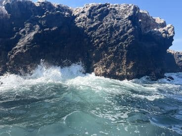 An unclear image of rocky formations with waves crashing against them, lacking identifiable features or subjects.