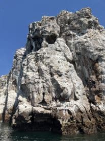 A stunning view of a rugged rock formation rising from the water, showcasing the natural beauty of the coastline — perfect for nature lovers and scenic boat tours.