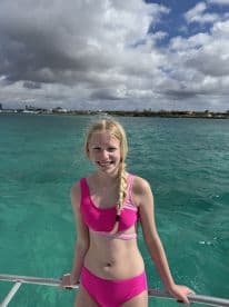 A young girl smiles while enjoying a sunny day on a boat, surrounded by beautiful turquoise waters — a perfect moment for family adventures on the sea.