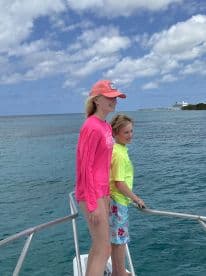 Two children enjoy the ocean breeze while standing on the bow of a boat, capturing a joyful moment on their aquatic adventure.