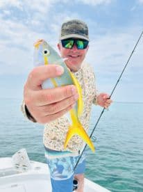 A man proudly displays his catch while fishing on a boat, showcasing the thrill of a successful day on the water.