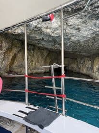 Inside view of a boat's cabin, showcasing seating and the stunning blue waters outside, perfect for exploring coastal caves.
