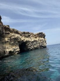 A stunning view of rocky cliffs and a cave along the coastline, showcasing the natural beauty of the ocean — perfect for scenic boat tours and exploration.