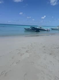 A sleek speedboat is docked on a pristine beach, surrounded by clear turquoise waters — perfect for a day of relaxation and adventure.