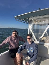 Two friends enjoy a sunny day on the boat named 'Elysian,' capturing the essence of friendship and adventure on the water.