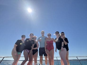 A cheerful group of friends poses together on a boat under the bright sun, capturing the essence of a fun-filled day at sea.