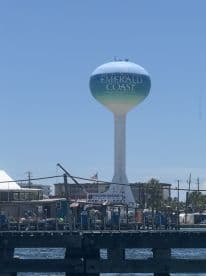 A water tower marked 'Emerald Coast' stands prominently against a clear blue sky, showcasing a local landmark in Northwest Florida.