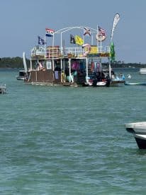 A vibrant floating bar with various inflatable toys and amenities, perfect for a fun day on the water. Guests enjoy the sun and water activities at this lively spot.