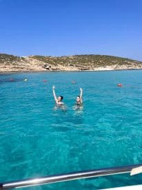 Two friends joyfully swim in crystal-clear turquoise waters, celebrating their day out in nature — a perfect snapshot of fun and adventure.