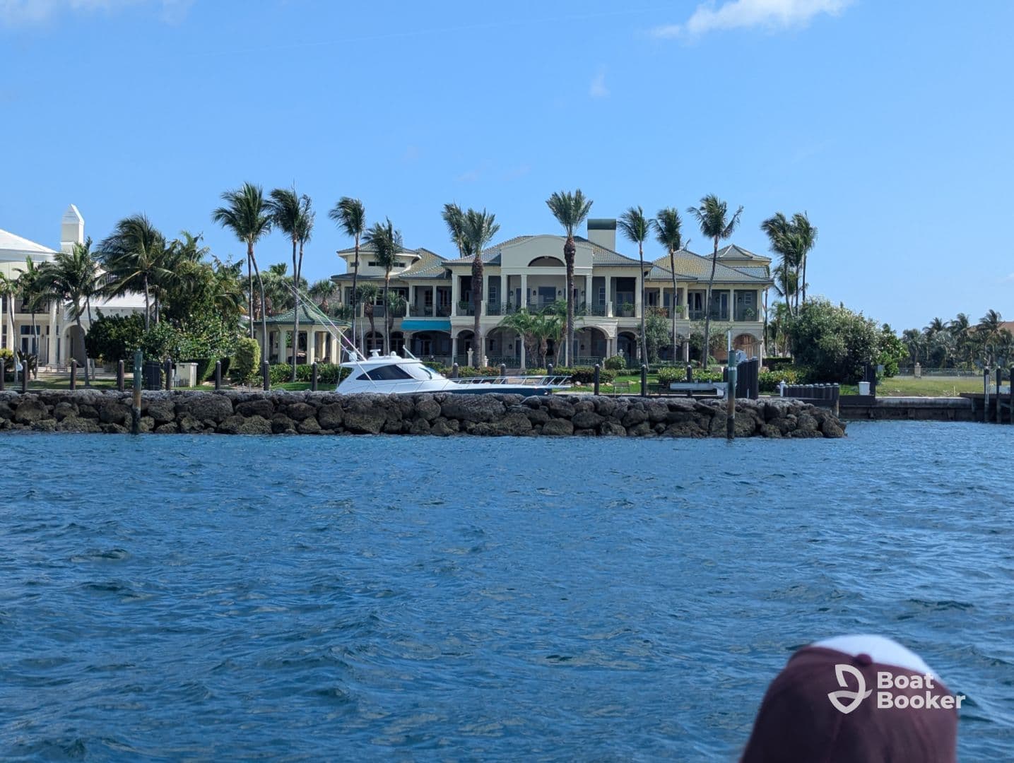 A sleek yacht is docked along a scenic waterfront, surrounded by lush palm trees and luxurious homes, perfect for a day of relaxation on the water.