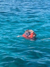 A child enjoys snorkeling in crystal-clear waters, showcasing the excitement of underwater exploration — a perfect family adventure.