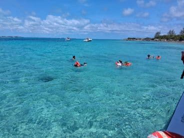 A lively group enjoys snorkeling in the crystal-clear waters, showcasing the beauty of marine life and the excitement of underwater exploration.