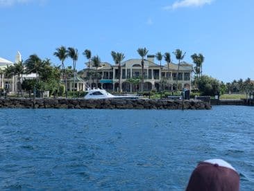 A sleek yacht is docked along a scenic waterfront, surrounded by lush palm trees and luxurious homes, perfect for a day of relaxation on the water.
