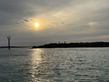 A serene sunset view with silhouettes of people on the rocks, capturing the tranquil beauty of the coastline.