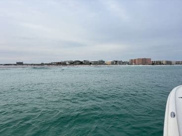 A scenic view of the coastline with beach houses lining the shore, showcasing the tranquil waters and inviting atmosphere perfect for a day out on the boat.