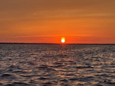 A breathtaking sunset over tranquil waters, creating a picturesque scene perfect for romantic evenings or peaceful boat rides.