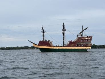 The Buccaneer, a striking pirate-themed ship, sails through calm waters, offering a unique experience for adventurers and families alike.