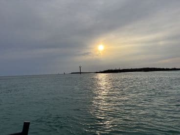 A serene sunset over calm waters, highlighting the beautiful coastline and creating a picturesque scene perfect for evening boat trips.