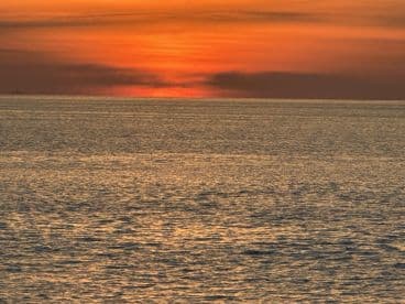 A stunning sunset over calm waters, creating a picturesque backdrop ideal for evening boat cruises.