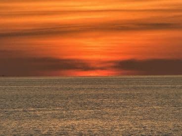 A stunning sunset over the ocean, creating a picturesque backdrop perfect for evening boat cruises.