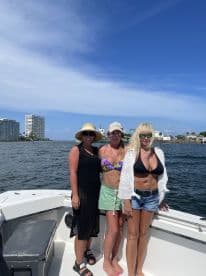 Three friends enjoy a sunny day on the boat, capturing a fun moment together against a vibrant waterfront backdrop.