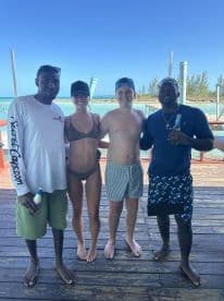 A cheerful group poses for a photo at a beachside location, capturing a fun moment during their boating adventure.