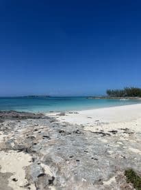 A stunning view of a serene beach with clear turquoise waters and a rocky shoreline, perfect for a relaxing day in paradise.